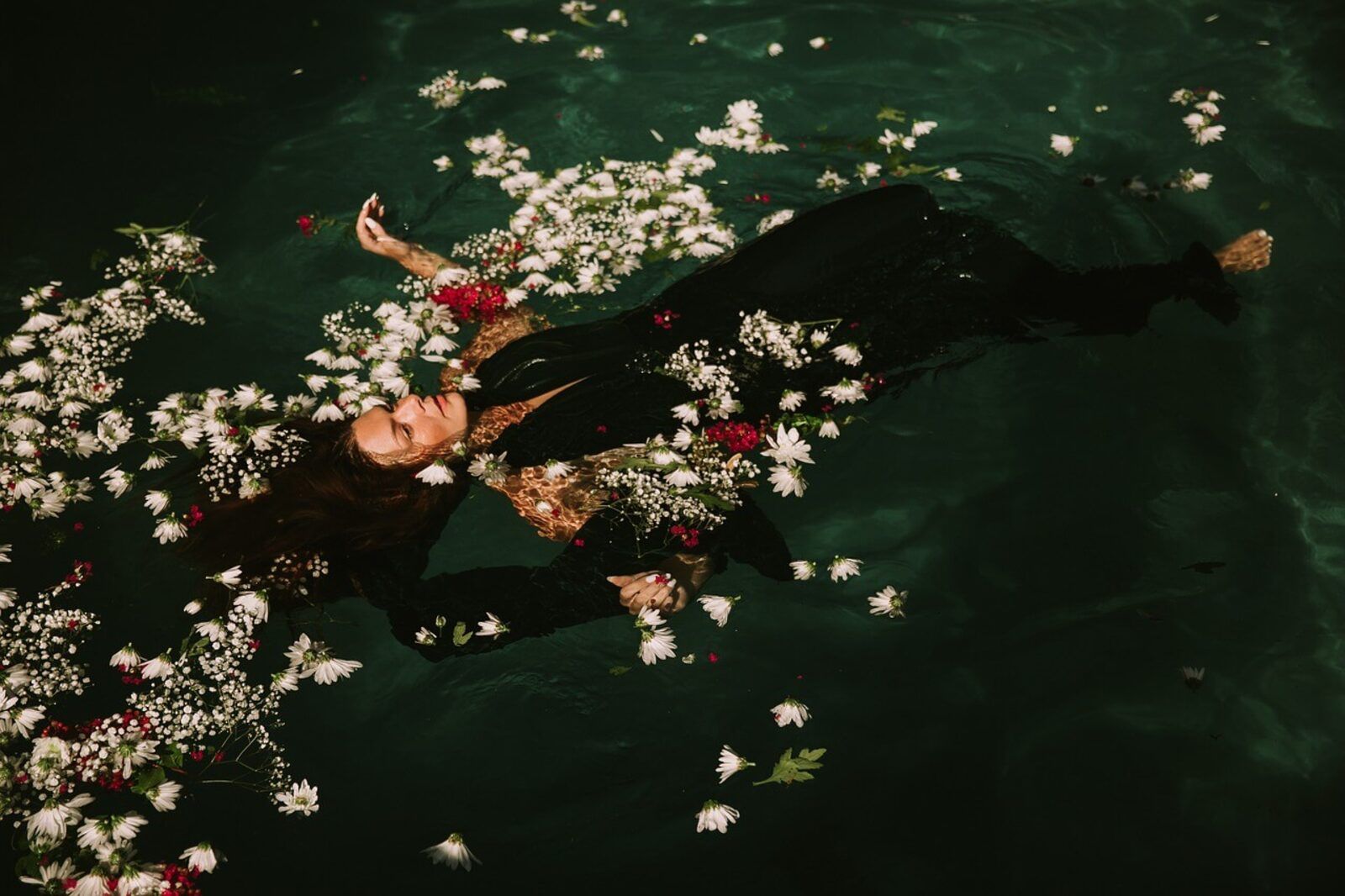 Persona flotando en el agua rodeada de pequeñas flores blancas