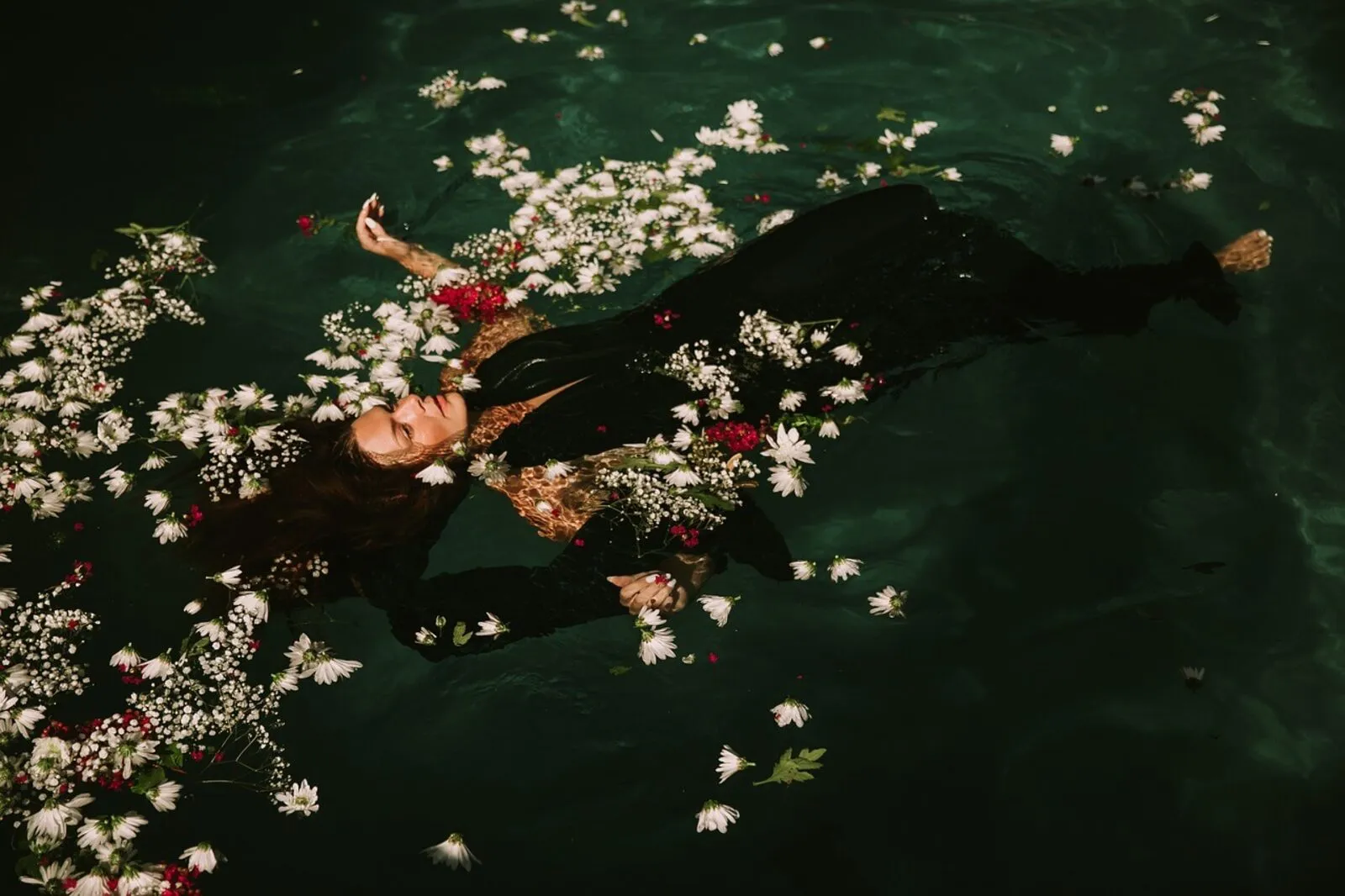 Persona flotando en el agua rodeada de pequeñas flores blancas