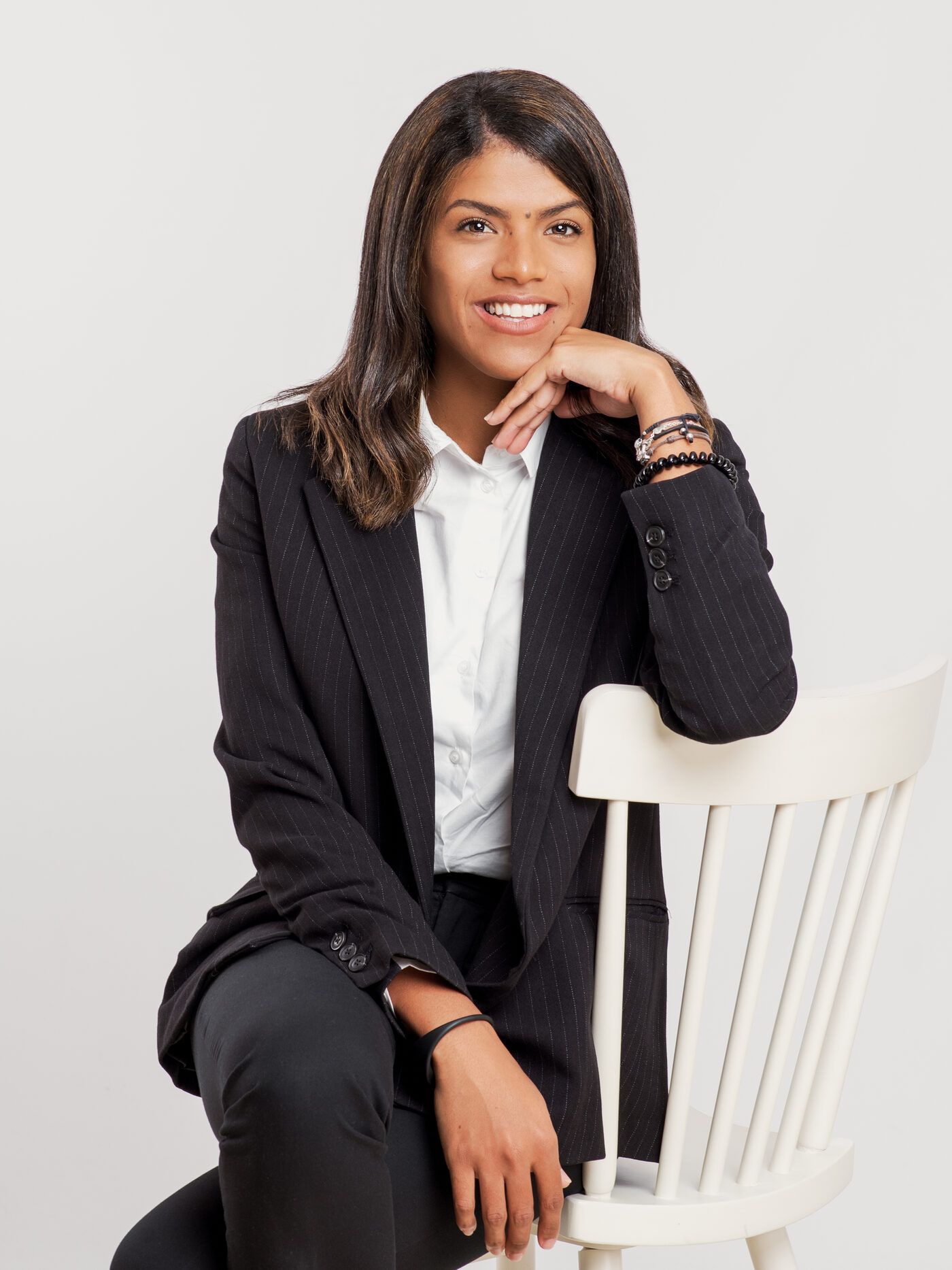 Zoraimy Sánchez sentada en una silla blanca, con americana negra, sonriendo